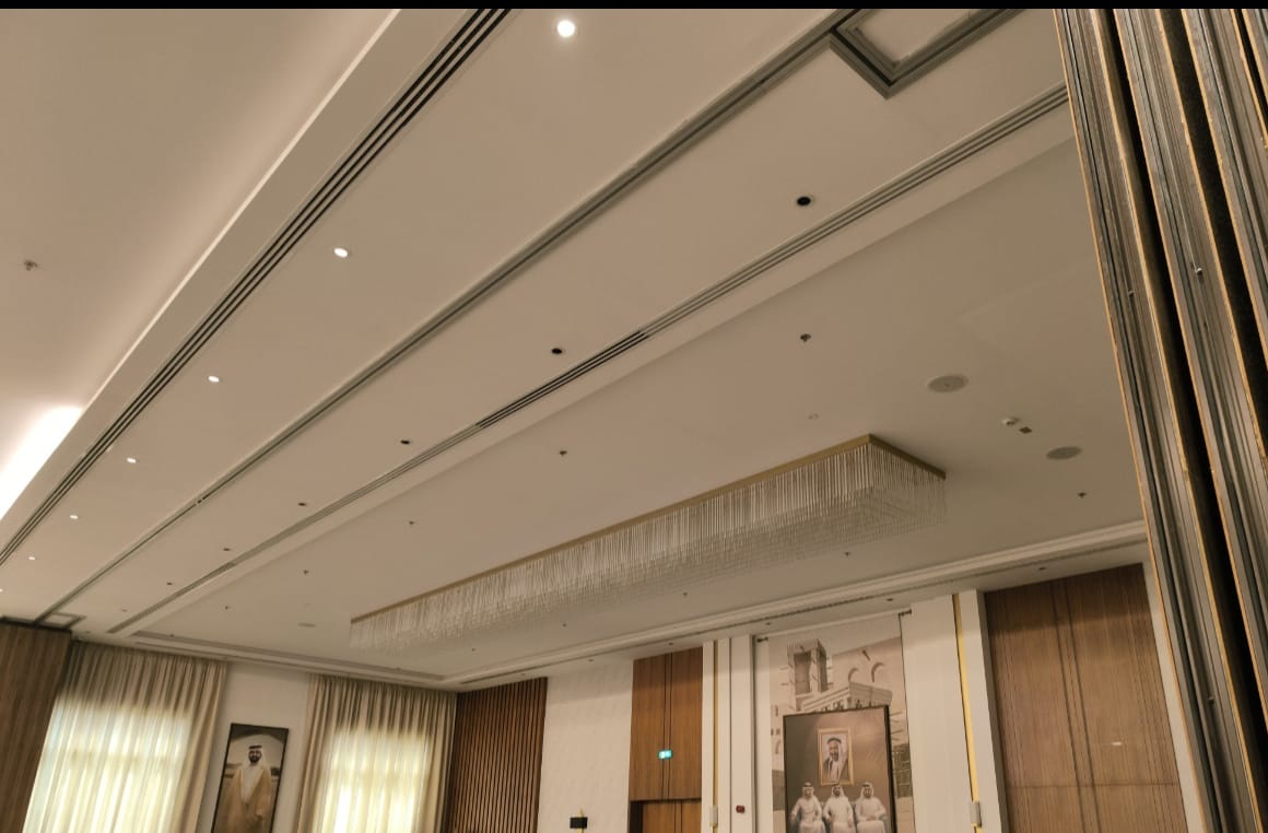 The secondary linear crystal chandelier suspended within a recessed ceiling panel in the finished majlis