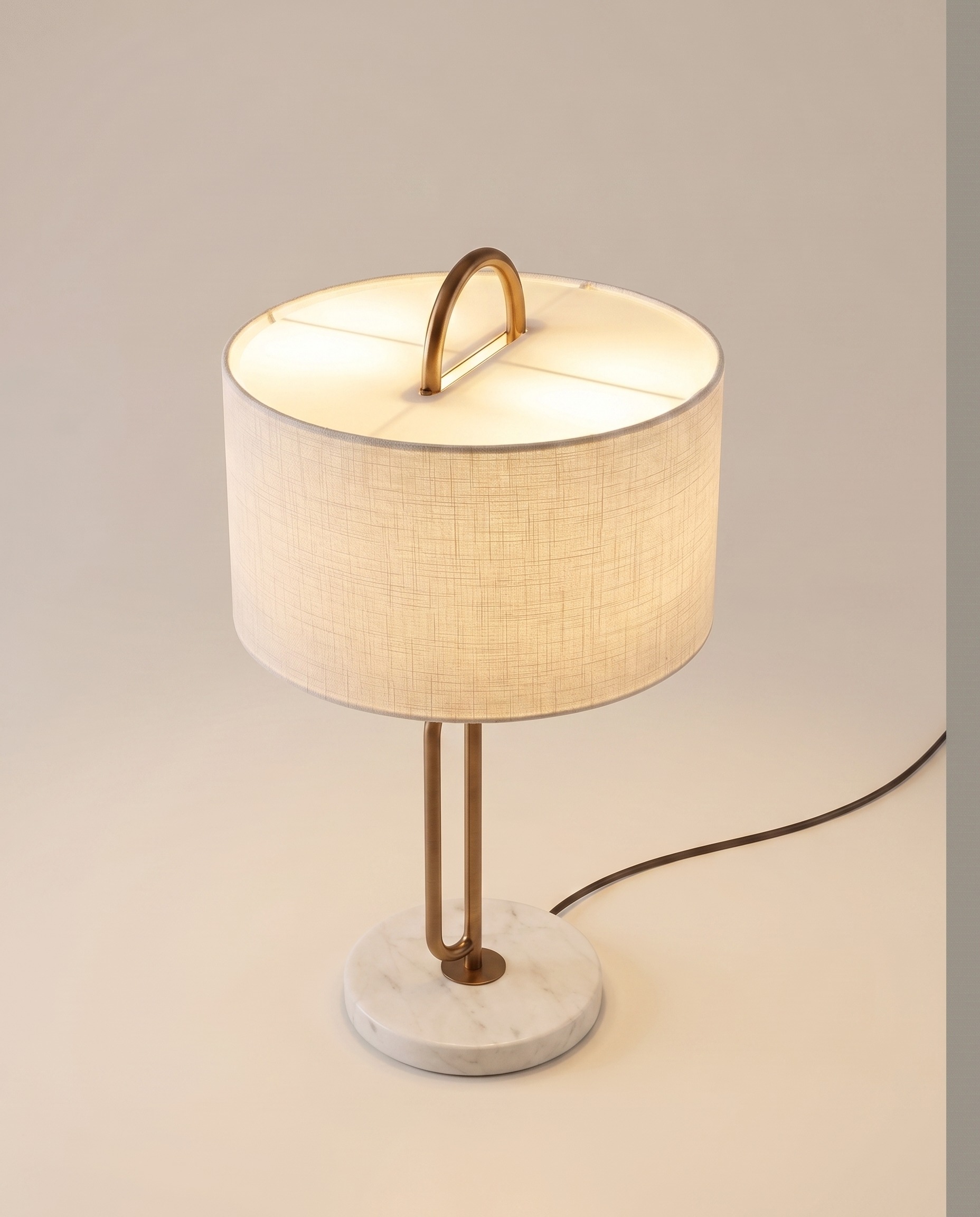 Marble-base table lamp with linen drum shade and copper arch, lit