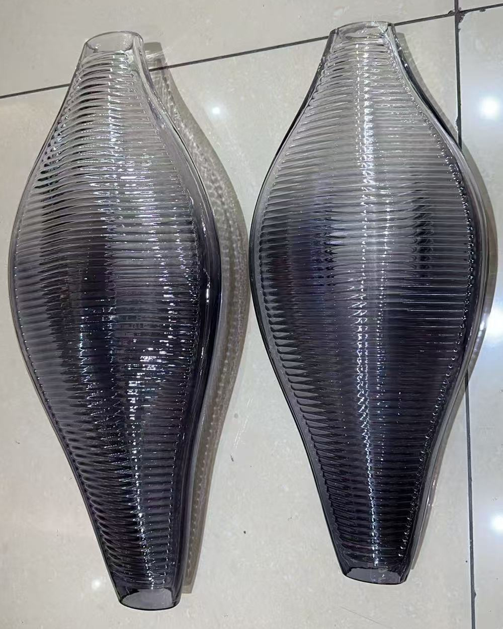 Two ridged glass shells after tinting, graded from dark at the base to clear at the top